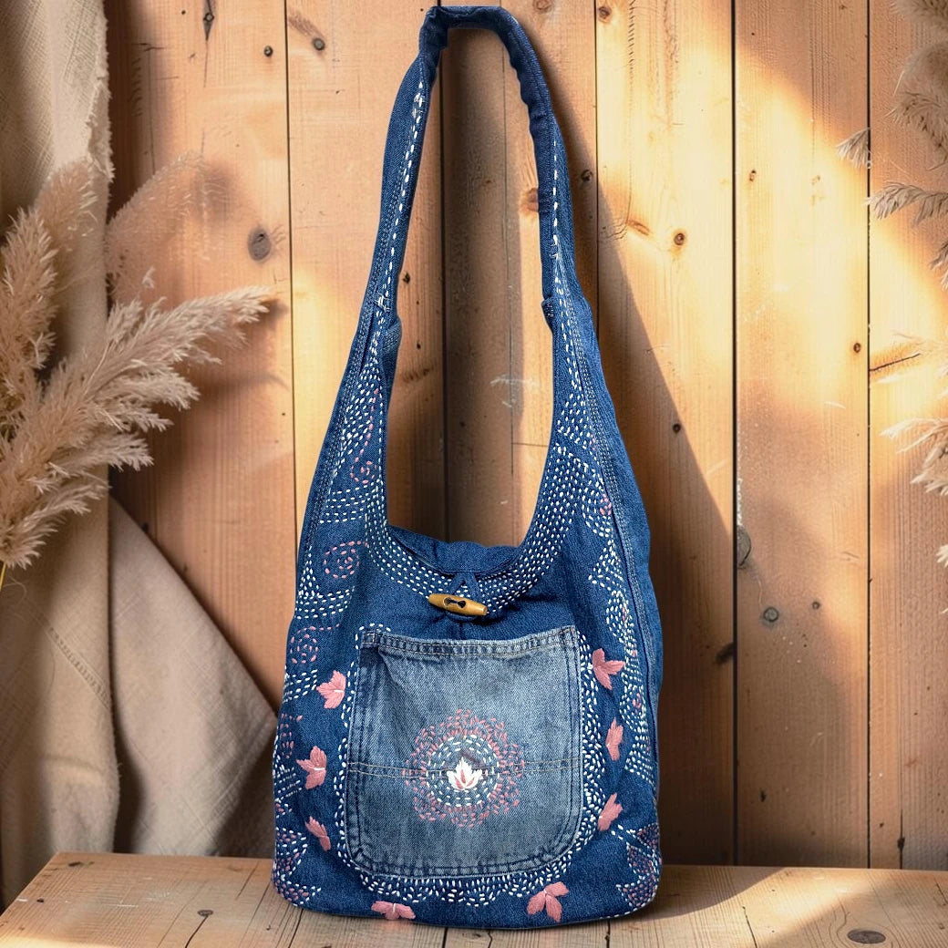 Bidora denim hobo shoulder bag with pink and white floral embroidery, wooden toggle closure, and wide shoulder strap.