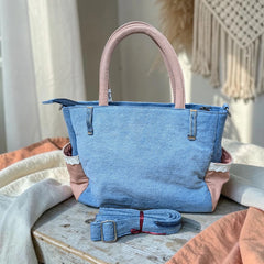 Bidora upcycled blue denim handbag with dusty rose handles, lace-trimmed side pockets, and detachable shoulder strap.