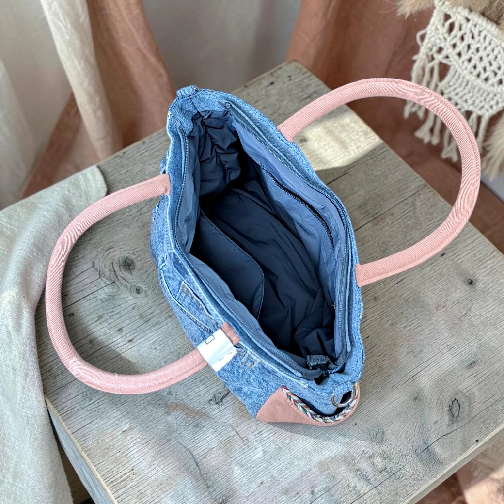 Bidora upcycled blue denim handbag with pink handles and a spacious lined interior, viewed from above.