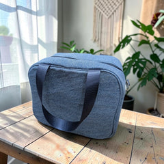 Bidora insulated lunch tote bag in blue denim-look fabric with black nylon handles sitting on a wooden table.