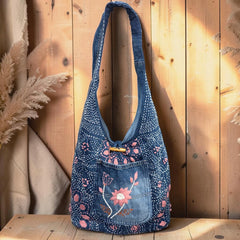 Bidora indigo denim hobo shoulder bag with pink floral embroidery, wooden toggle closure, and slouchy silhouette.
