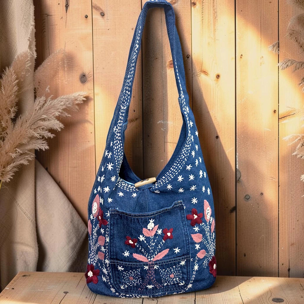 Bidora blue denim hobo shoulder bag with floral embroidery, front pocket, and wooden toggle closure