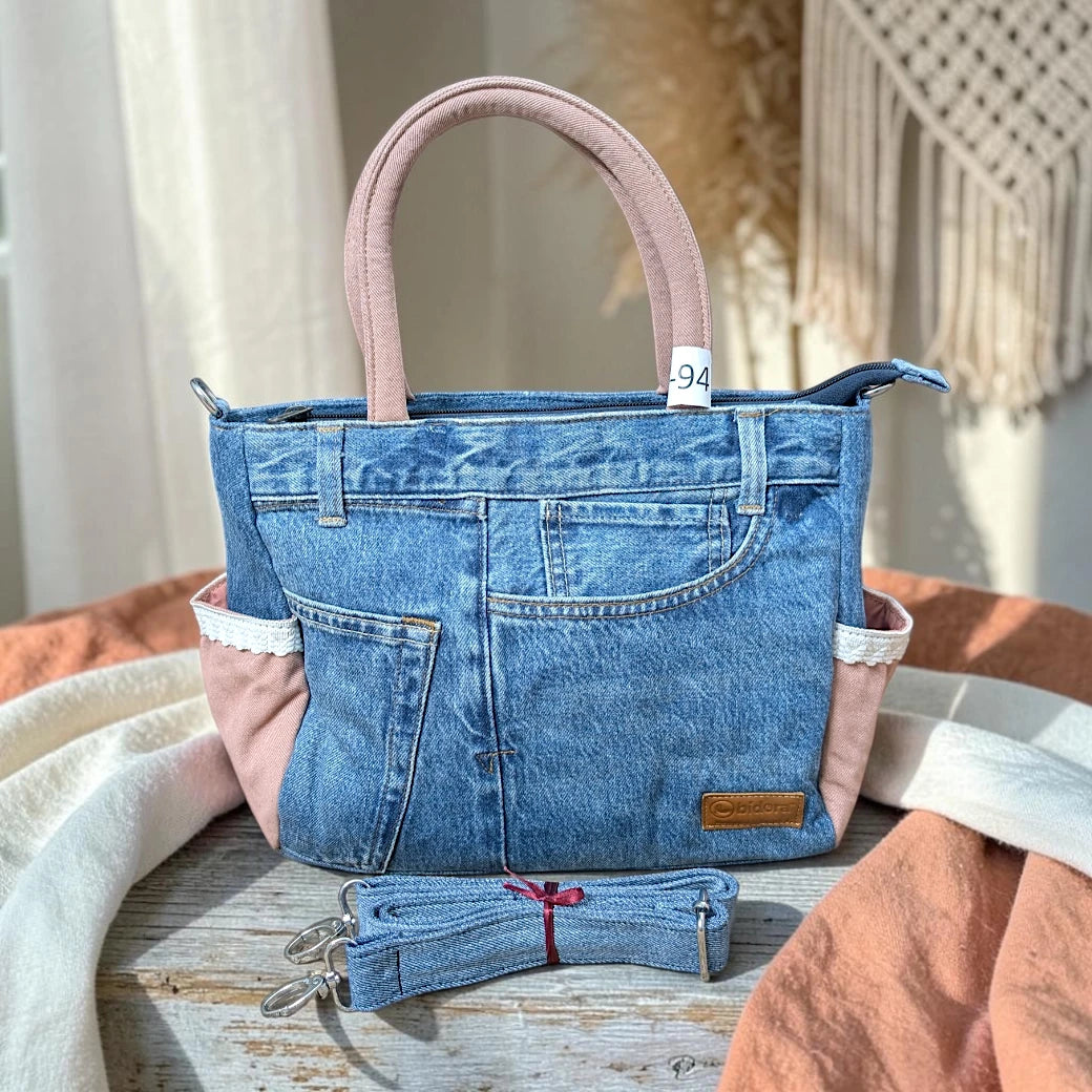 Bidora upcycled denim handbag with pink fabric accents, lace trim, top handles, and a detachable shoulder strap.