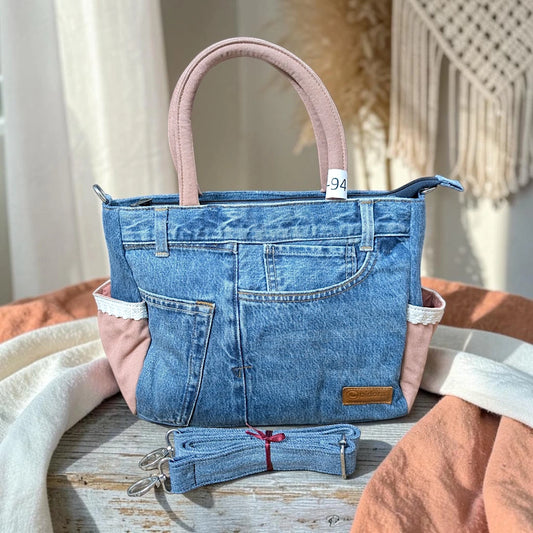 Bidora upcycled denim handbag with pink fabric accents, lace trim, top handles, and a detachable shoulder strap.