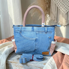 Bidora upcycled blue denim handbag with dusty rose handles, side pockets with lace trim, and detachable shoulder strap.
