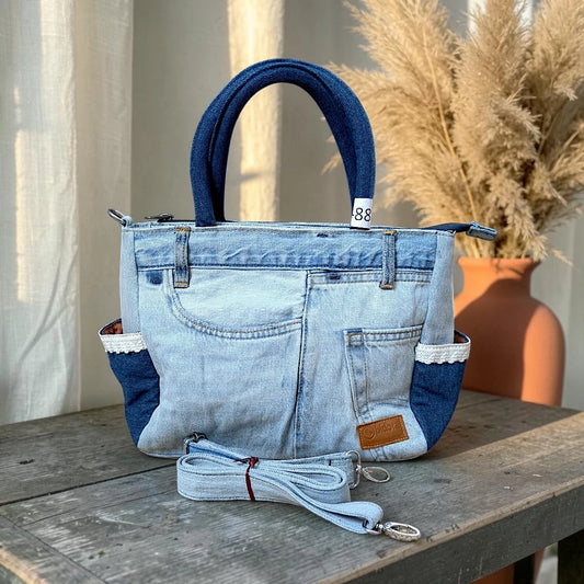 Bidora upcycled denim handbag featuring patchwork light and dark wash fabric, lace-trimmed side pockets, and strap.