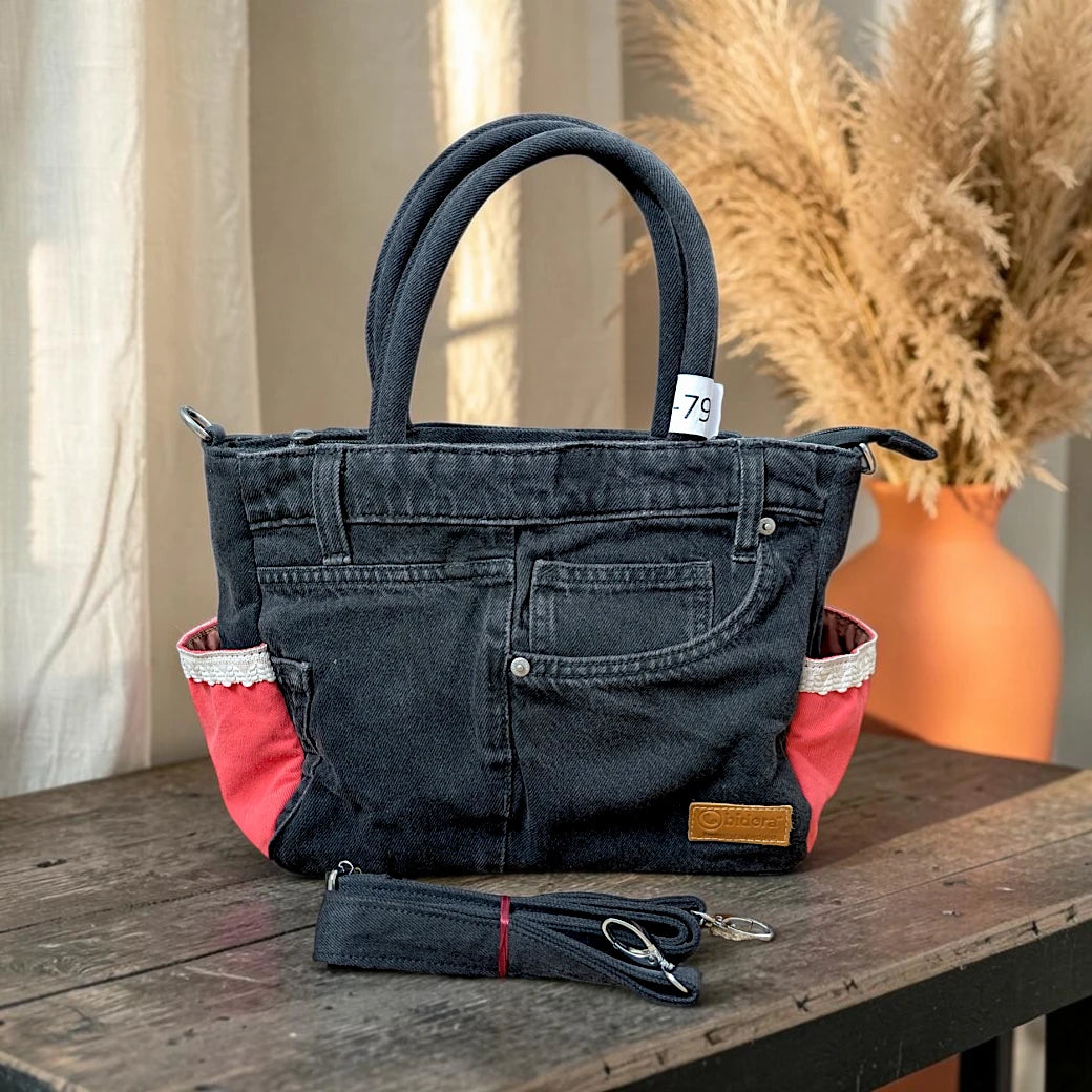 Bidora upcycled black denim handbag with red side panels, lace trim, top handles, and detachable shoulder strap.