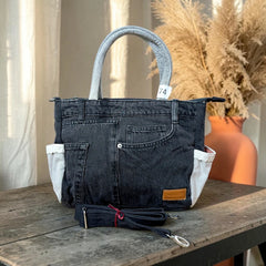 Bidora black upcycled denim tote handbag with light-wash handles, exterior pockets, and detachable shoulder strap.