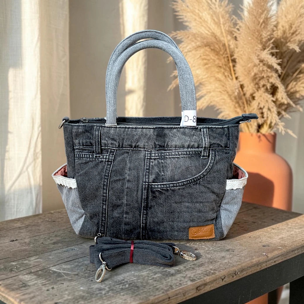Bidora charcoal grey denim handbag with lace-trimmed side pockets, top handles, and a detachable shoulder strap.