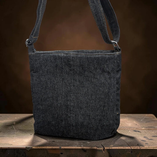 Bidora upcycled dark denim crossbody shoulder bag with an adjustable strap sitting on a rustic wooden surface.