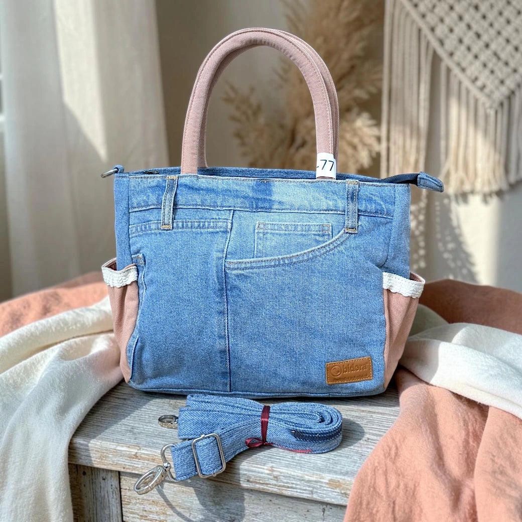 Bidora upcycled blue denim handbag with dusty pink handles, lace trim, exterior pockets, and detachable shoulder strap