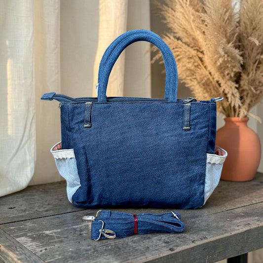 Bidora two-tone denim handbag with lace-trimmed side pockets, top handles, and a detachable shoulder strap.