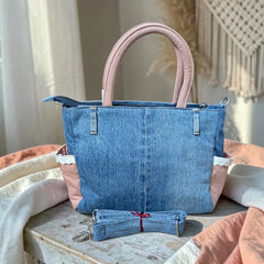 Bidora upcycled denim handbag with pink handles, lace trim, side pockets, and a detachable shoulder strap.