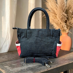 Bidora dark wash denim handbag with red side pockets, white lace trim, top handles, and a detachable shoulder strap.