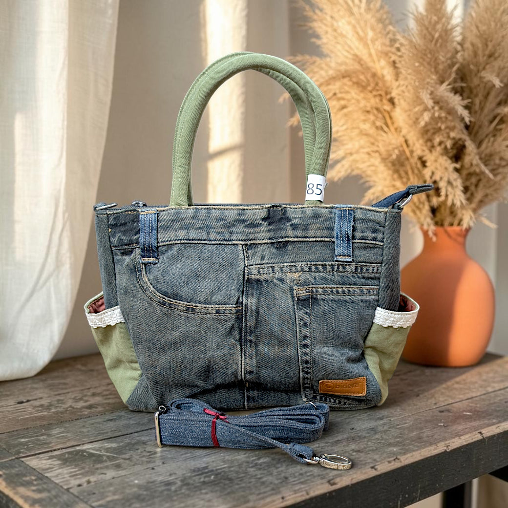Bidora upcycled blue denim handbag with sage green handles, lace trim, side pockets, and detachable shoulder strap.