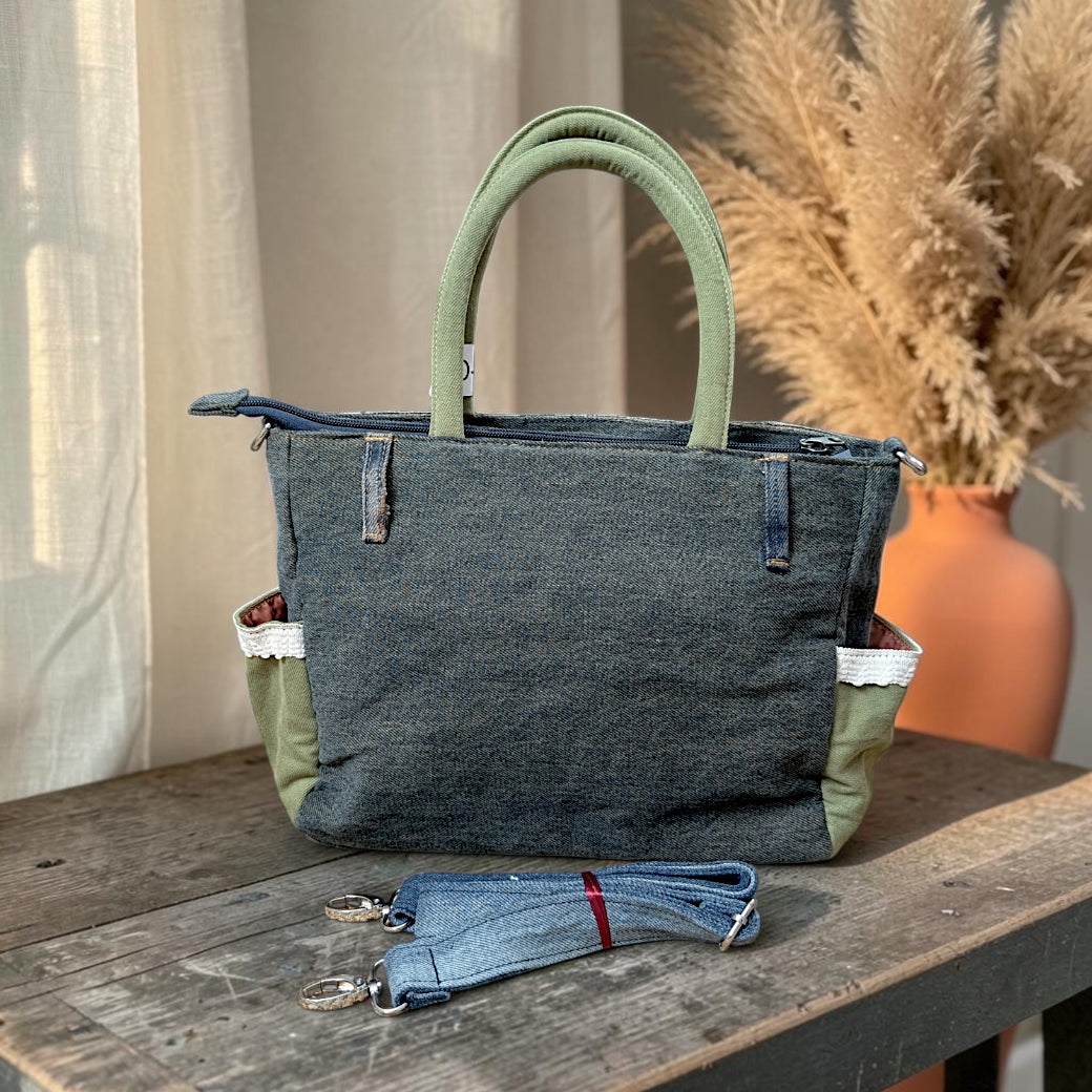 Bidora upcycled denim handbag with sage green handles, lace trim, side pockets, and a detachable shoulder strap.