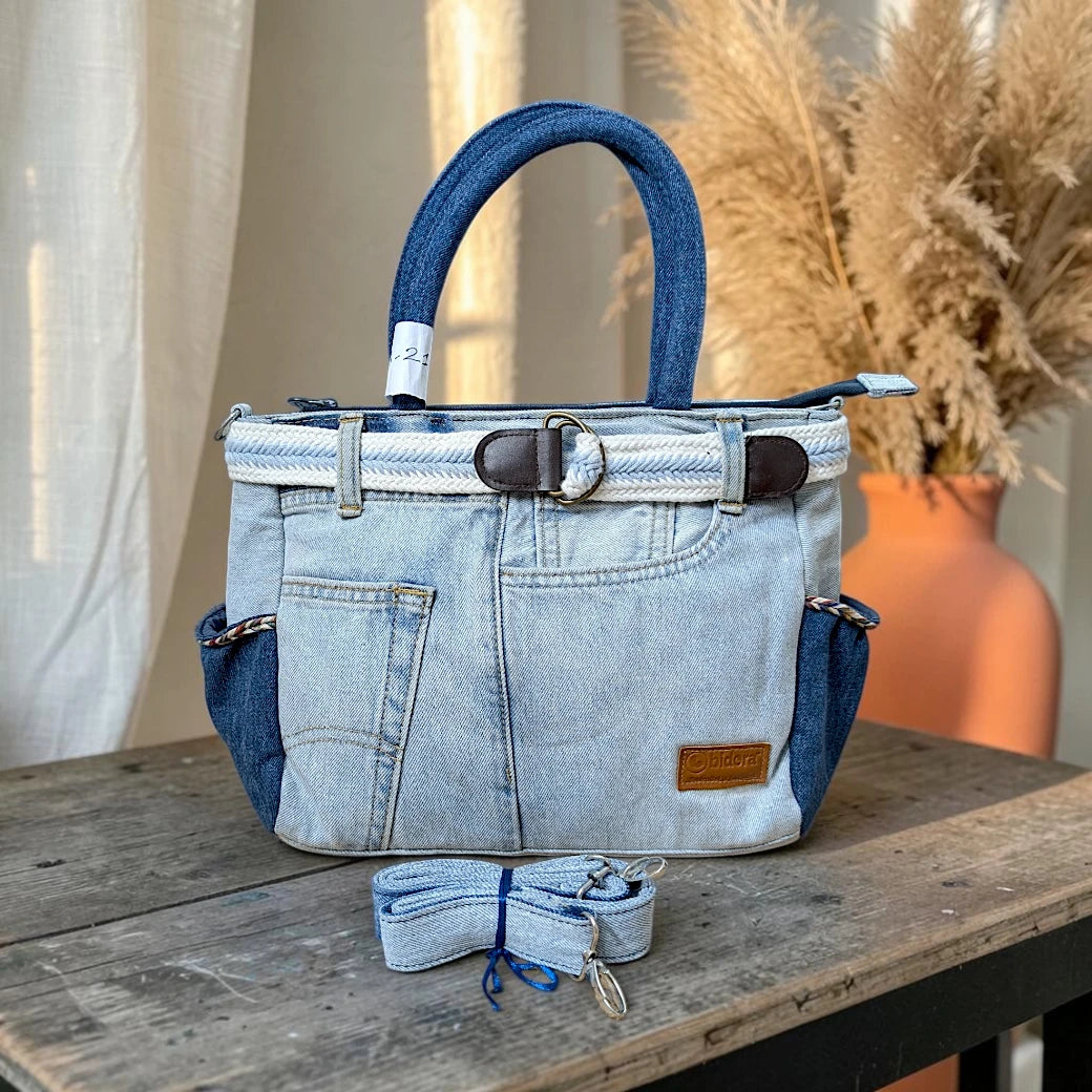 Bidora two-tone blue denim handbag with belt trim, side pockets, sturdy handles, and detachable shoulder strap.