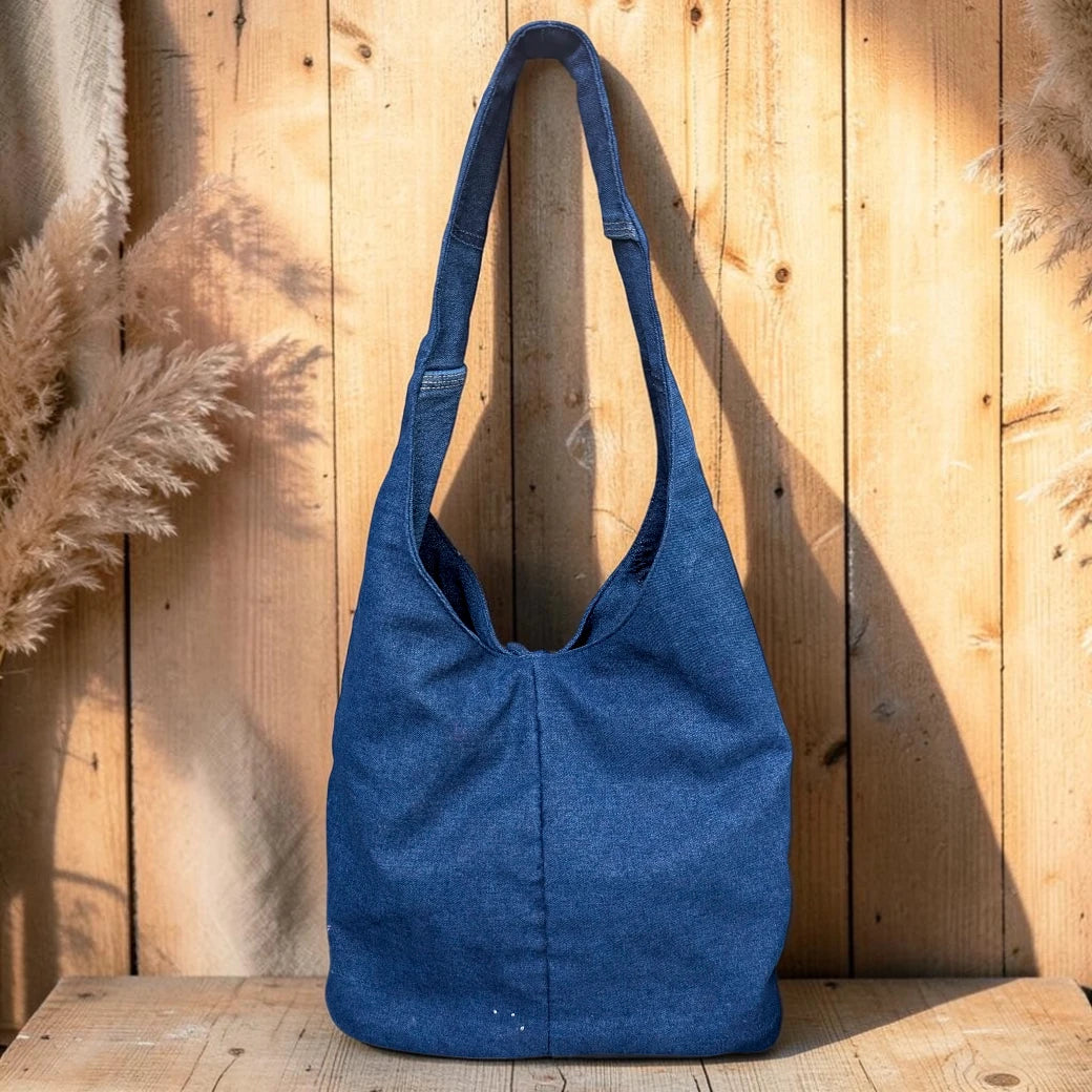 Bidora denim hobo shoulder bag with a slouchy silhouette against a rustic wooden background.