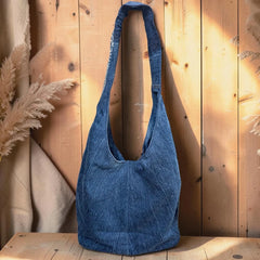 Bidora slouchy indigo denim hobo shoulder bag with artisanal embroidery against a rustic wooden background.