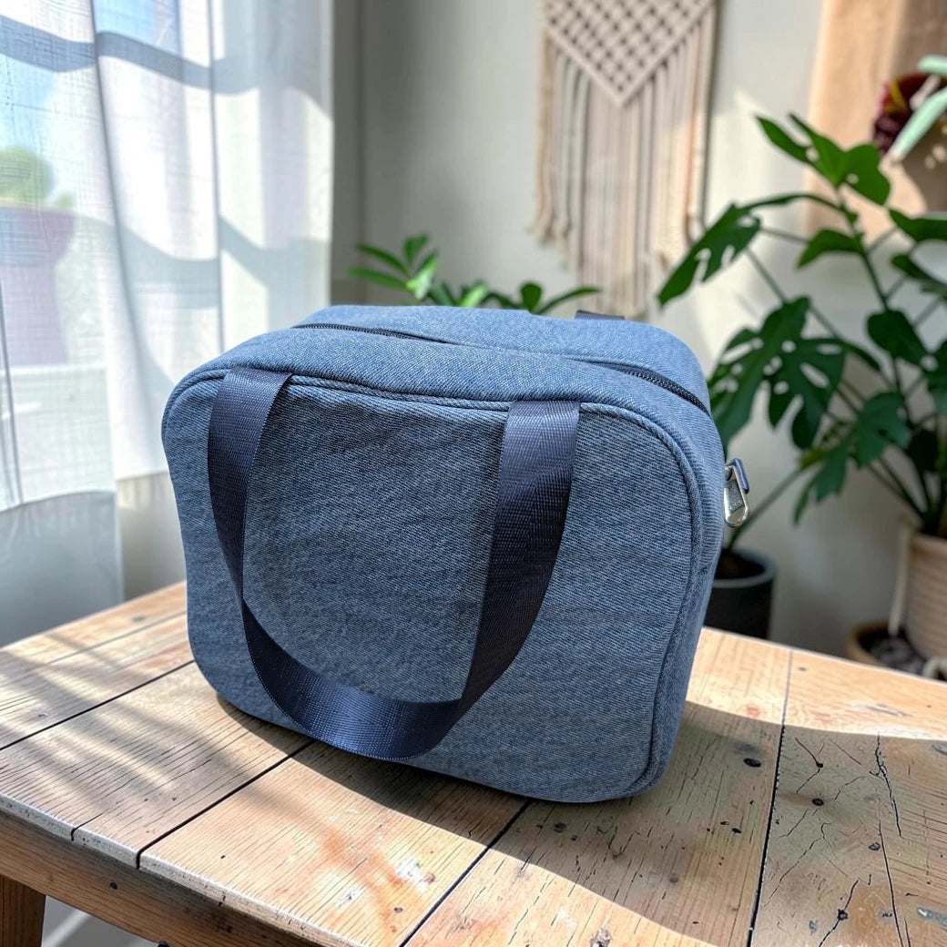 Bidora insulated lunch tote bag in blue denim-look fabric with black nylon handles sitting on a wooden table.