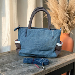 Bidora handcrafted blue denim tote bag with brown panels, white lace trim, and a detachable shoulder strap.