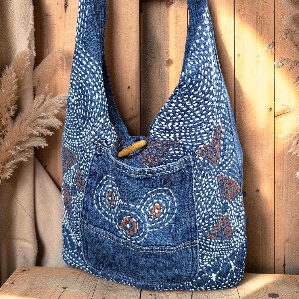 Bidora indigo denim hobo shoulder bag with intricate white and brown hand-stitched embroidery and wooden toggle closure