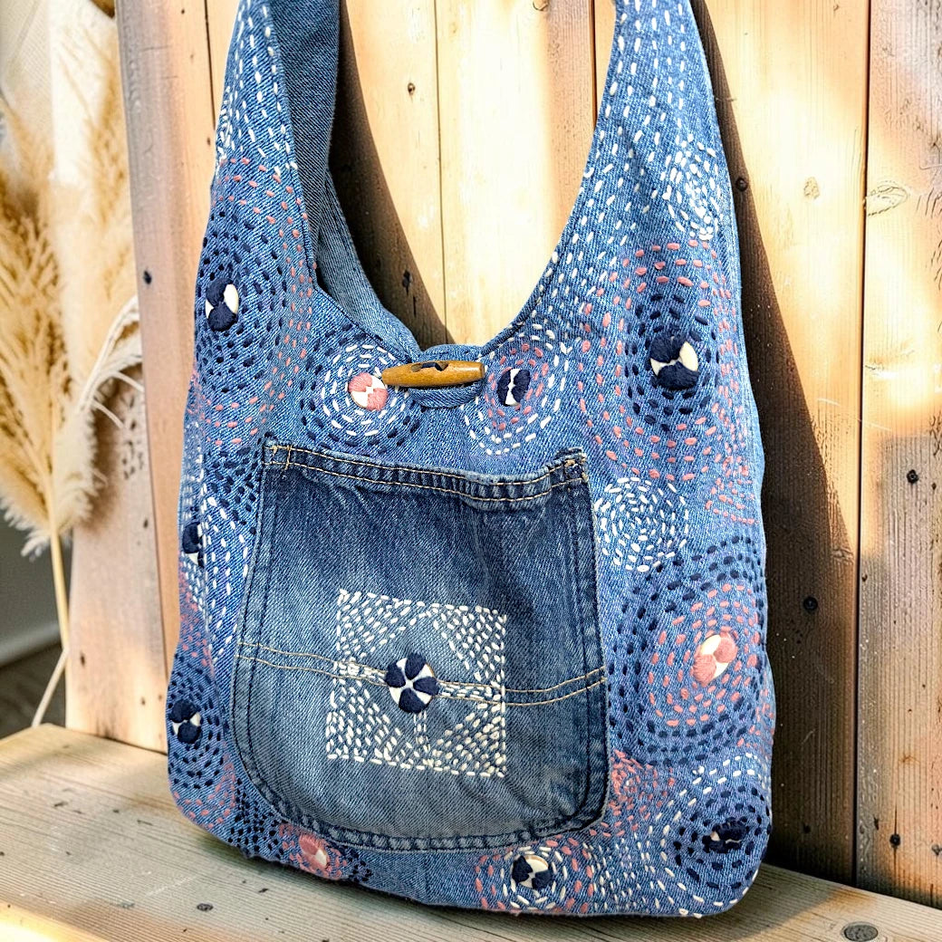 Bidora denim hobo shoulder bag with patchwork construction, hand-stitched circular embroidery, and wooden toggle closure