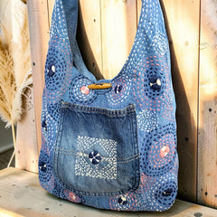 Bidora denim hobo shoulder bag with patchwork construction, hand-stitched circular embroidery, and wooden toggle closure