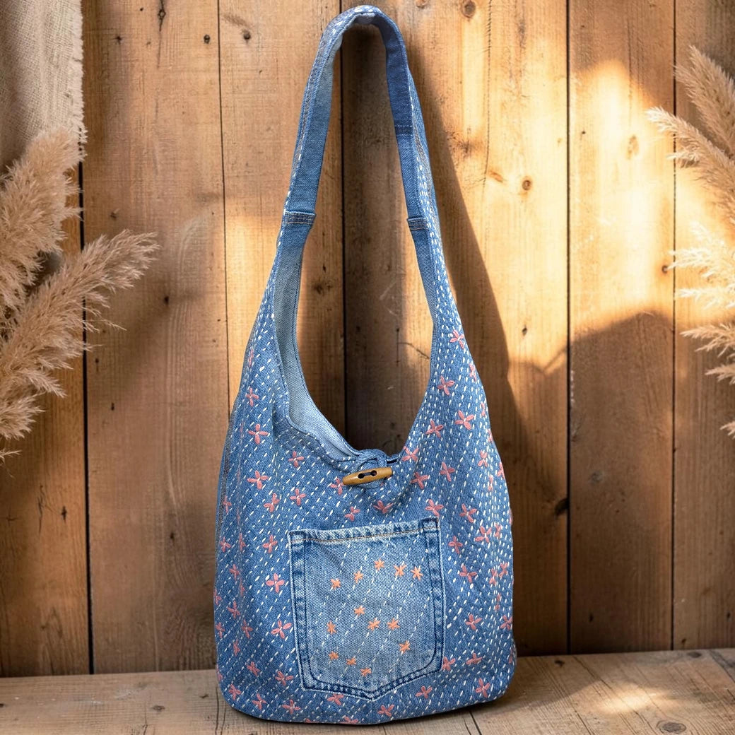 Bidora denim hobo shoulder bag with pink and white floral embroidery, exterior pocket, and rustic wooden toggle closure.