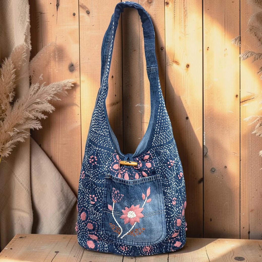 Bidora indigo denim hobo shoulder bag with pink floral embroidery, wooden toggle closure, and slouchy silhouette.