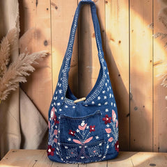 Bidora blue denim hobo shoulder bag with floral embroidery, front pocket, and wooden toggle closure