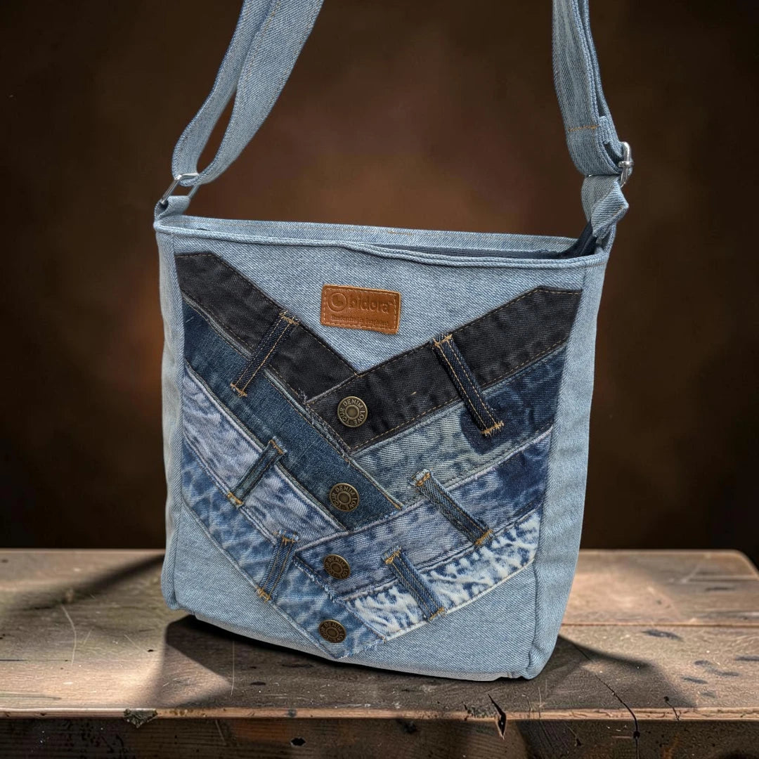 Bidora patchwork denim crossbody bag with light and dark wash fabric, button accents, and a branded leather patch.