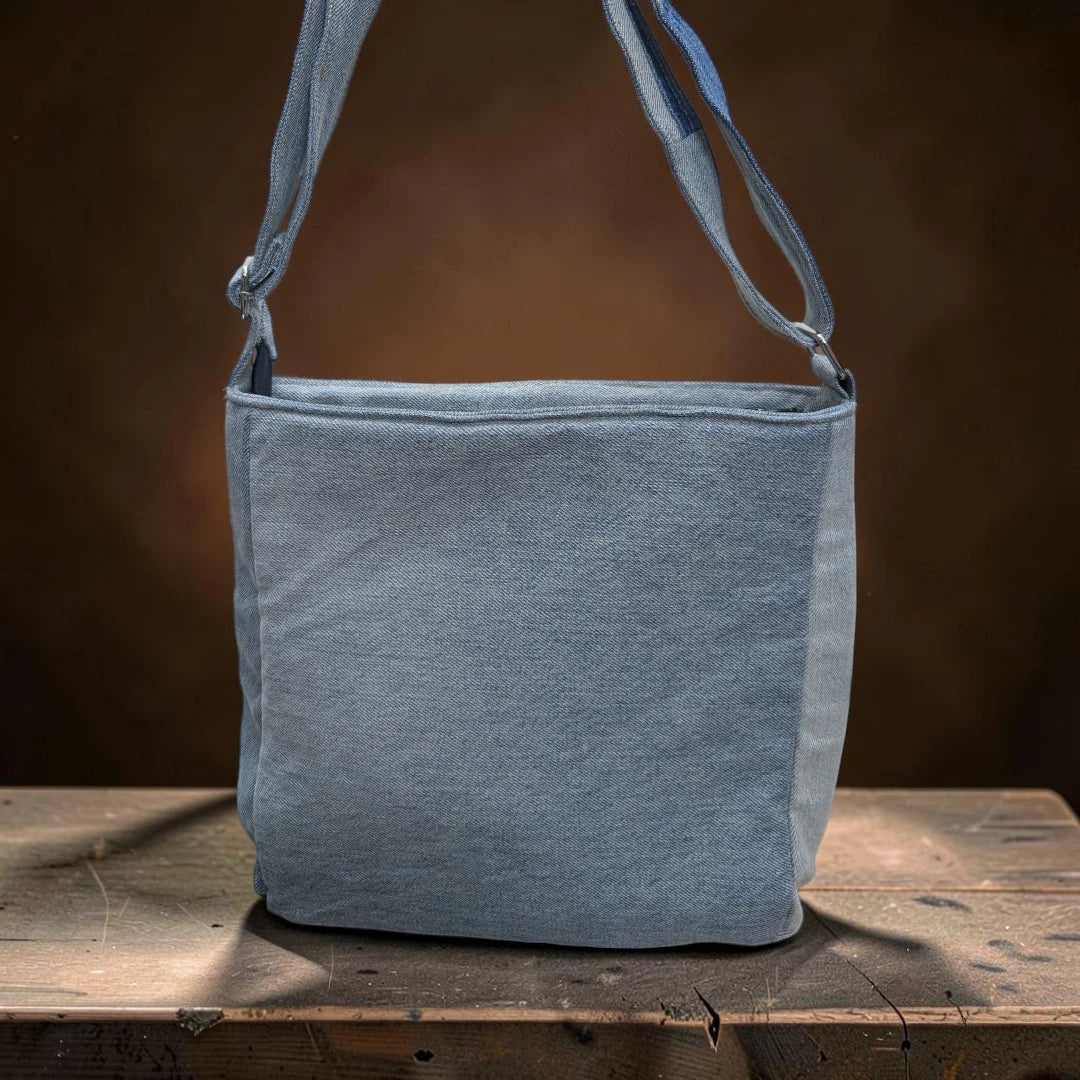 Bidora patchwork denim crossbody bag with adjustable shoulder strap, featuring light blue repurposed fabric textures.