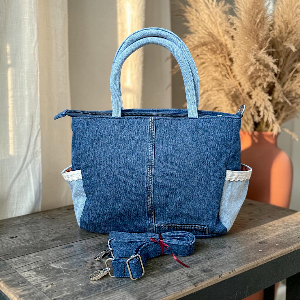 Bidora two-tone denim handbag with lace-trimmed side pockets, top handles, and a detachable shoulder strap.