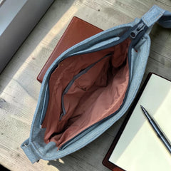 Interior view of a Bidora upcycled denim crossbody bag with a pink lining, zipper pocket, and adjustable strap.