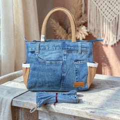Bidora upcycled blue denim handbag with tan handles, lace trim, and a detachable shoulder strap on a wooden table.