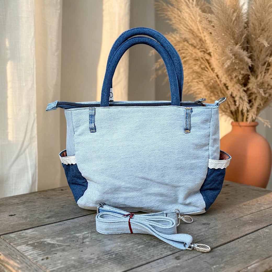 Bidora upcycled denim handbag with patchwork light and dark wash textures, lace-trimmed side pockets, and shoulder strap