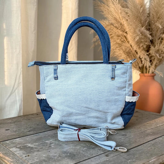 Bidora upcycled denim handbag with patchwork light and dark wash textures, lace-trimmed side pockets, and shoulder strap