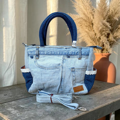 Bidora upcycled denim handbag featuring patchwork light and dark wash fabric, lace-trimmed side pockets, and strap.