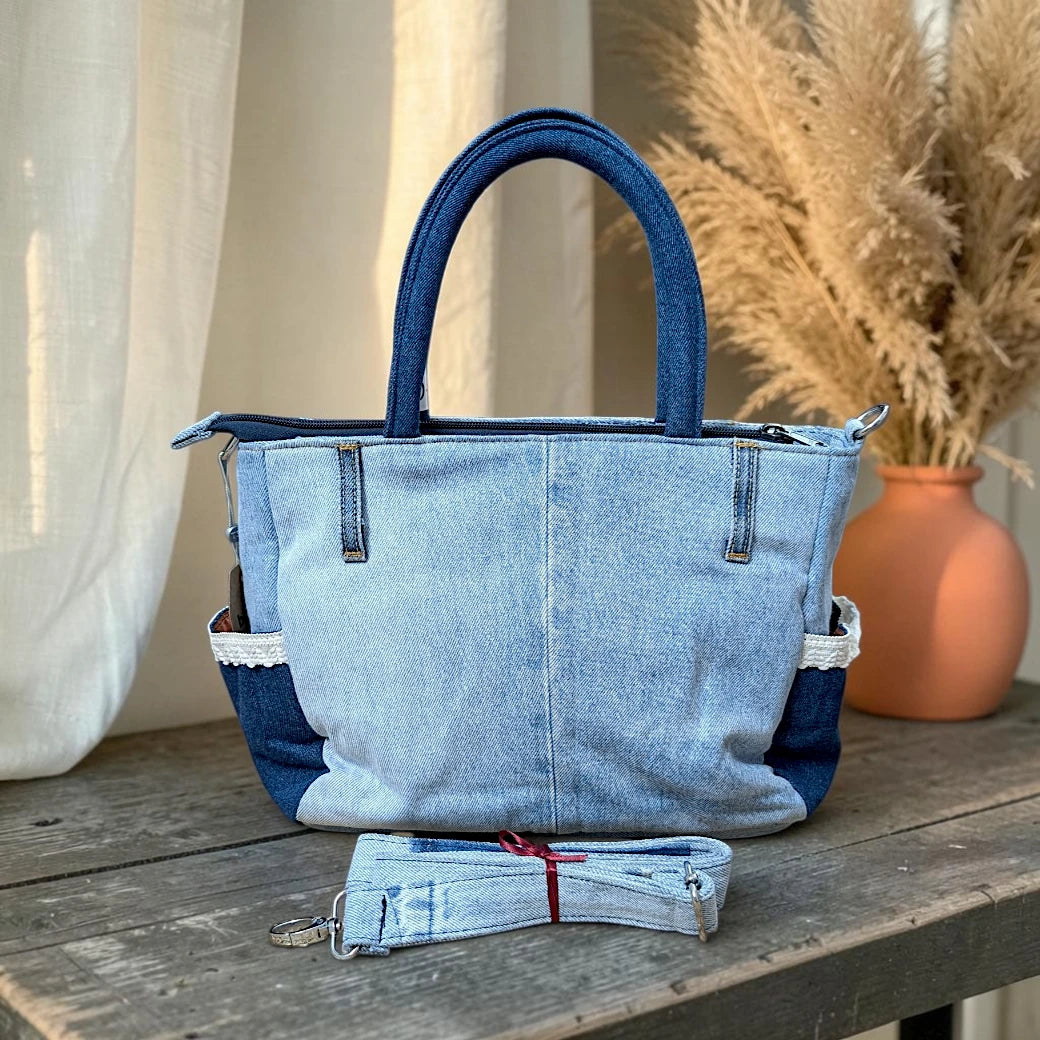 Bidora upcycled light-wash denim tote handbag with dark blue handles, side pockets, and a detachable shoulder strap.