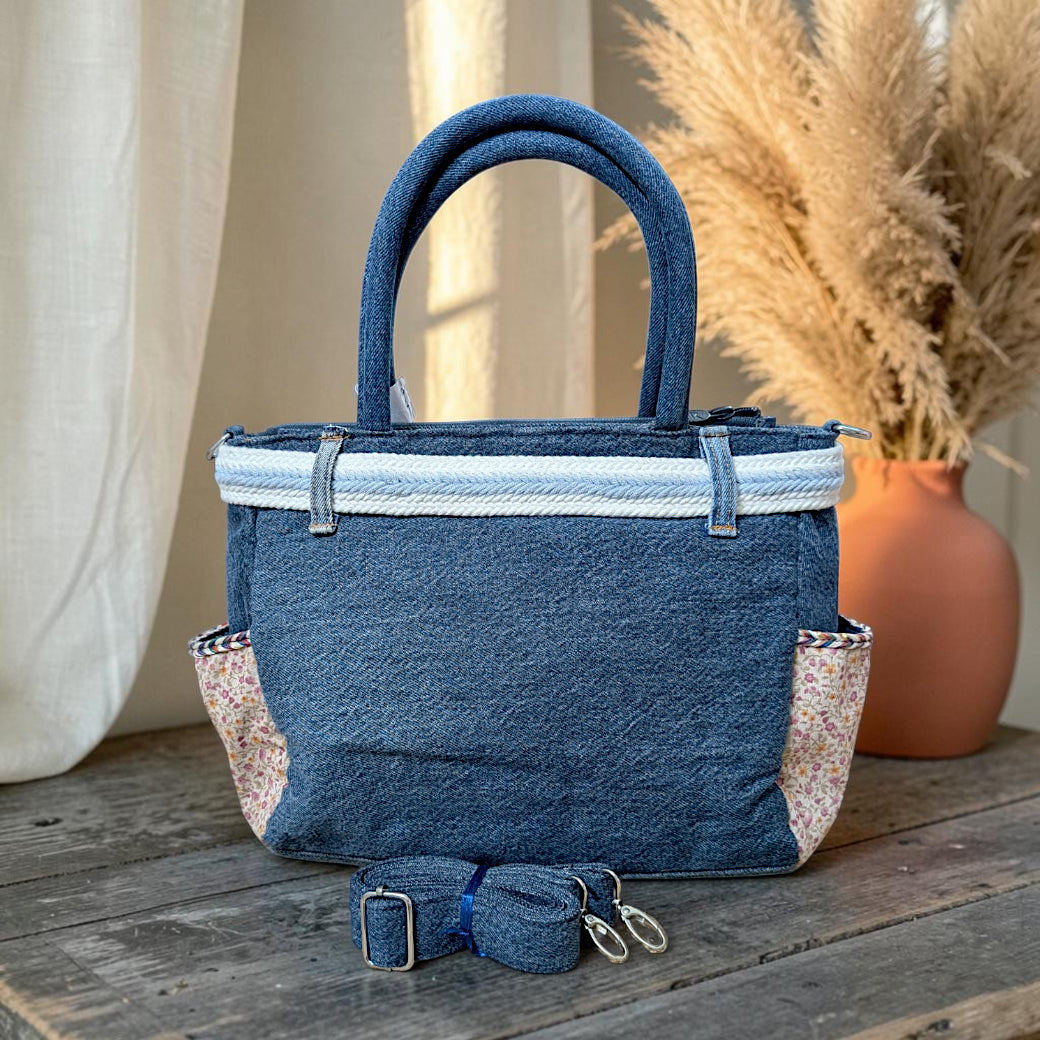Bidora upcycled blue denim tote handbag with floral side pockets, white braided belt detail, and detachable strap.